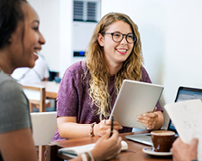 Three colleagues smile as they conduct a meeting over coffee.